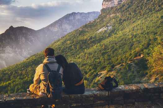 couples sitting in while facing mountain