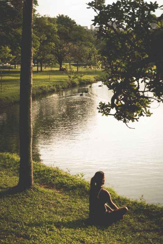 woman sitting on grass by lake